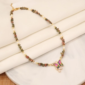 Detail of beaded butterfly necklace with colorful rhinestones and cross pendant on a tray