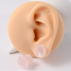 Detail of pink rose quartz stone ear gauge plug on realistic silicone ear model