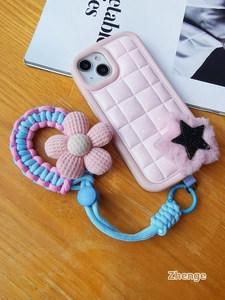 Pink puffer phone case with woven hand strap and plush star charm on wood background