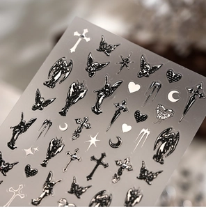 Macro shot of 3D gothic nail stickers featuring black silver angels and crosses