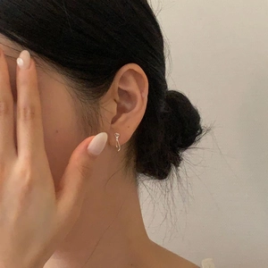 Close-up of minimalist 925 sterling silver bow knot earrings worn on an ear lobe