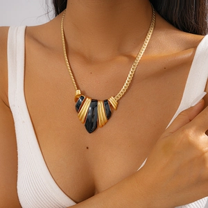 Detailed view of bohemian gold chain necklace with black enamel fan pendant on model