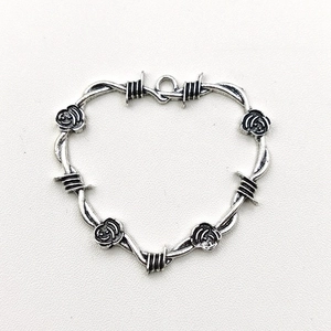 Macro view of antique silver heart pendant with thorny wire rose details on white background