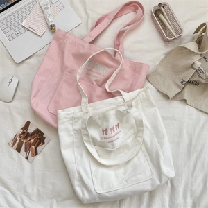 Detail of embroidered bows and poetic text on a canvas tote bag with front pocket