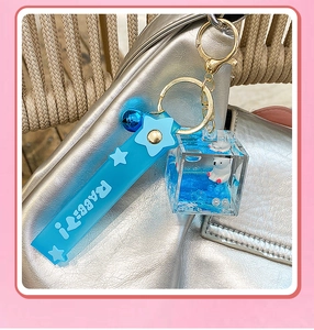 Close-up of blue polar bear liquid quicksand keychain hanging on a silver shoulder bag