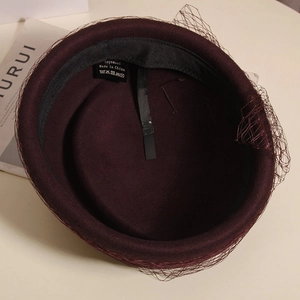 Detail view of burgundy wool beret with mesh veil, inner cotton sweatband and wash label