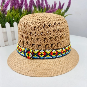Detailed macro view of the openwork breathable weave and ethnic embroidered band on straw hat