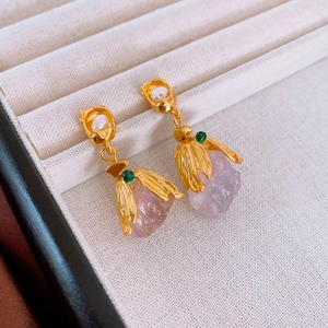 Macro view of gold tulip earrings with purple crystals, white pearls, and green gems