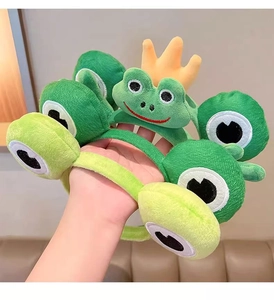 Close-up of cute green plush frog headbands with yellow crown detail for girls