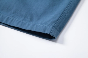 Macro view of blue cotton cargo shorts showing durable double-stitched hem and fabric texture