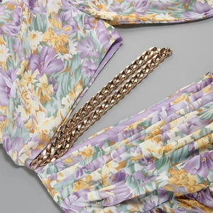 Detailed view of floral print dress with decorative chunky gold chain link accent