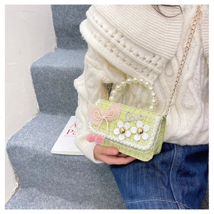 Detail of green tweed kids bag with pearl handle, cherry charm and daisy appliques