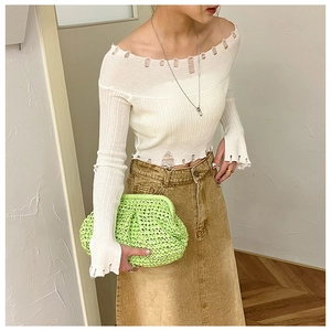 Detail of white off-shoulder knit sweater with trendy distressed rips and slim fit style