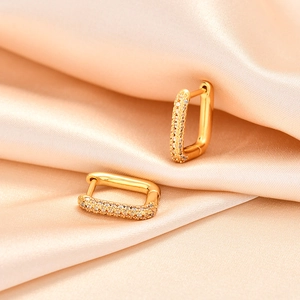 Elegant geometric gold huggie earrings with sparkling crystals on silk background