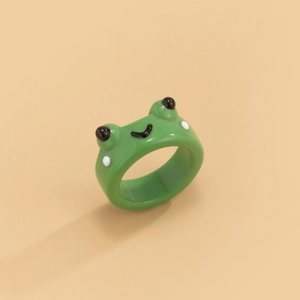 Detailansicht eines niedlichen grünen Froschrings aus Harz mit lächelndem Gesicht.