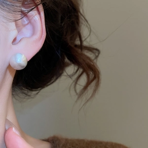 Close-up of minimalist brushed silver round stud earring worn on a model's earlobe