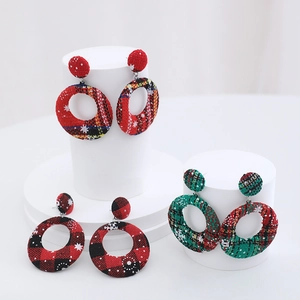 Close-up of red, green, and black plaid Christmas earrings with white snowflakes