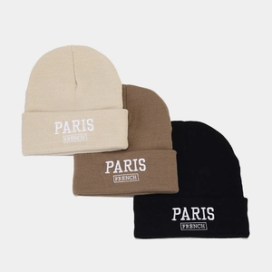 Detail of embroidered Paris French letters on three stylish knitted beanie color variants