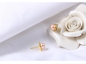 Detail view of pink freshwater pearl earrings with a golden square geometric base
