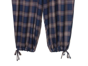 Detalle de pantalón de cuadros azul con cordón ajustable en el bajo y cierre de lazo