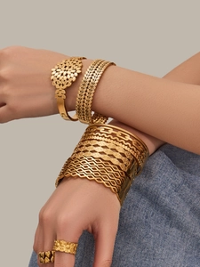 Detailed view of bohemian gold hollow floral bangles and leaf pattern rings on a model