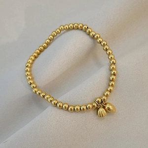 Elegant 18K gold beaded bracelet featuring a lotus pod and teardrop pendant on fabric
