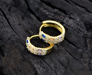 Macro shot of S925 sterling silver stamp and colorful cubic zirconia on gold hoop earrings