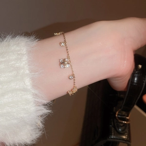 Detailed shot of golden charm bracelet with butterfly pendant and LOVE charm on wrist