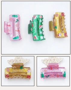 Close-up of Christmas acrylic hair claws with glitter finish and holiday patterns
