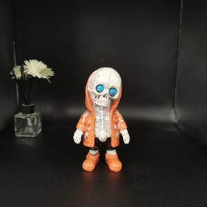 Detailed view of skull alien figurine in orange hoodie and shoes with blue eyes