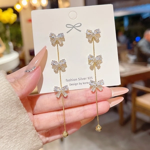 Detail of elegant gold bow tassel earrings with crystals on a 925 silver jewelry card