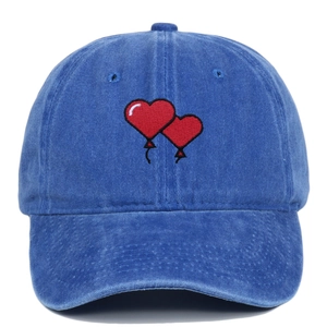 Detailed view of red heart balloon embroidery on washed cotton baseball cap in blue