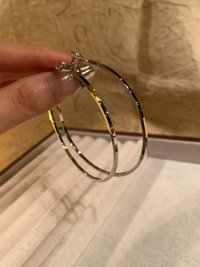 Macro view of large silver hoop earrings showing high-quality metallic texture and finish