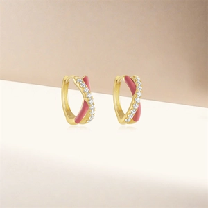 Close-up of golden hoop earrings featuring pink enamel and sparkling white zirconia details