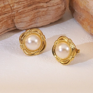 Detail of elegant gold-toned square stud earrings with central pearls on a textured stand