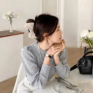 Elegant cream satin bow hair clip worn on a woman's bun for a minimalist Korean style