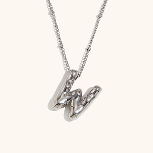 Macro shot of polished silver 18K plated stainless steel balloon letter W pendant necklace