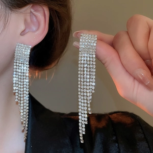 Détail des boucles d'oreilles pampilles argentées avec strass portées par un mannequin