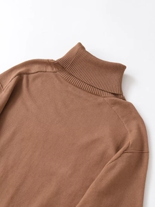 Close-up of brown knit sweater featuring ribbed turtleneck and fine wool texture detail