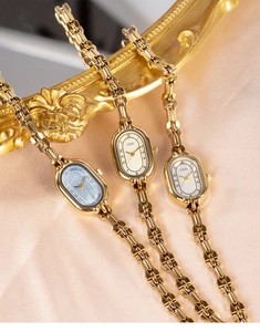 Detailed macro shot of vintage oval quartz watches with gold chain bands on silk