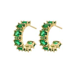 Detail view of gold vintage earrings with tiered green oval zircon stones in a C-shape