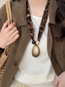 Detailed view of leopard print silk scarf necklace with a brown resin oval pendant