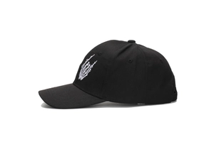 Detail view of white skull palm embroidery on a black cotton canvas baseball cap
