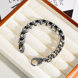 Detailed shot of a silver skull link bracelet resting in a premium wooden jewelry box