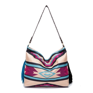 Detail of bohemian woven tote bag featuring colorful geometric prints and long side tassels