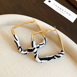Detailed view of geometric golden square earrings with black and white zebra pattern texture