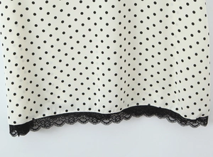 Detailed macro view of black polka dot pattern on cream fabric with delicate lace hem