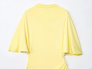Detail of bright yellow long dress featuring dramatic oversized layered ruffle sleeves