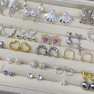 Macro display of diverse zircon butterfly pearl earrings and silver studs on velvet tray