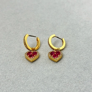 Französische Herzohrringe mit rotem Zirkon und Gold-Finish in minimalistischer Studioumgebung